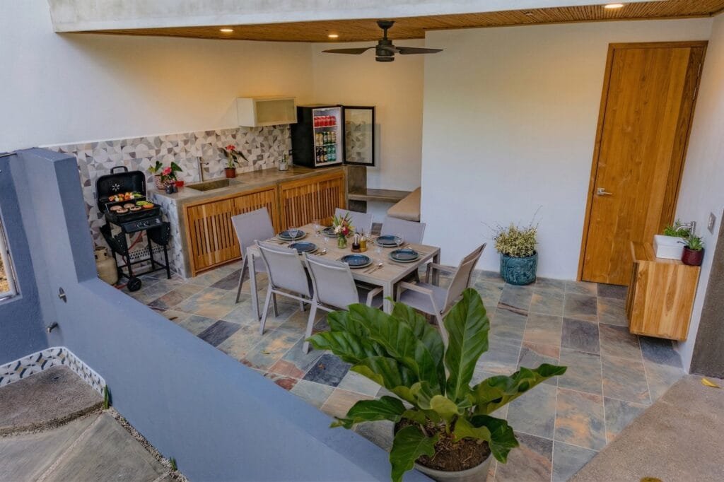 Cocina exterior techada con BBQ y mesa de comedor