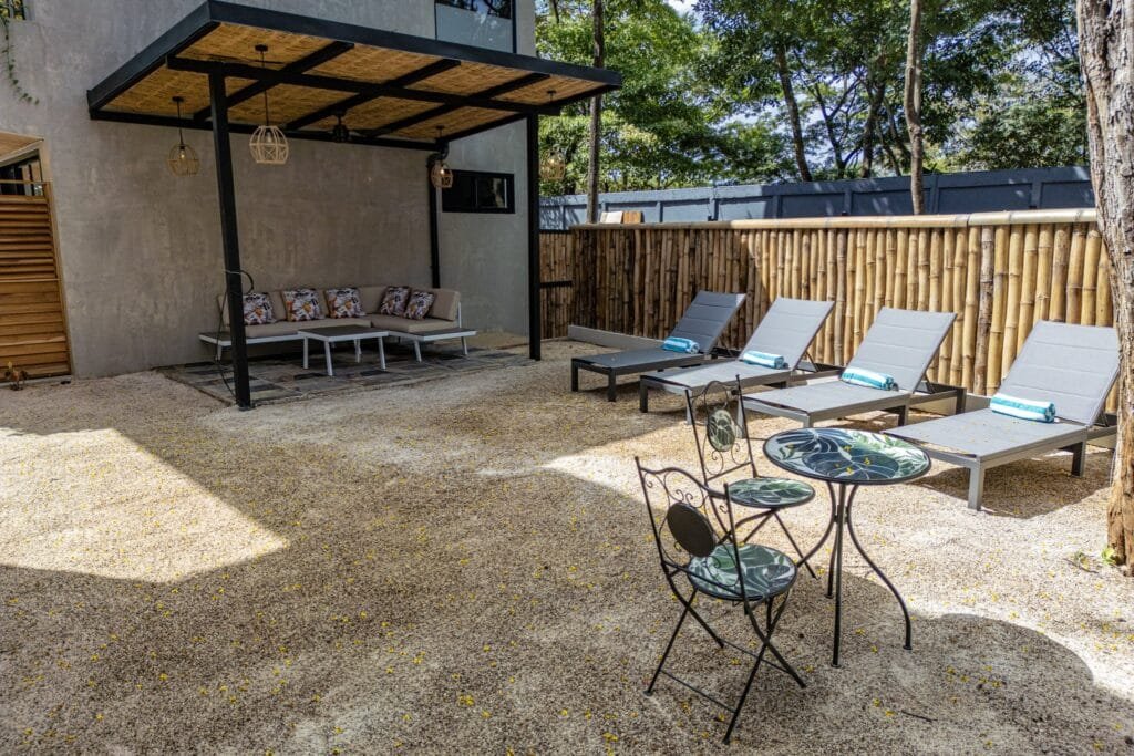 Lounge exterior bajo pérgola con sofá y camastros