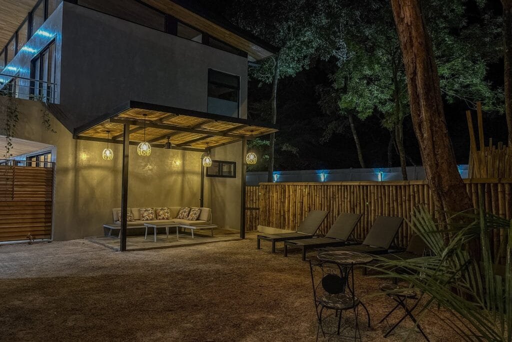 Lounge bajo pérgola iluminado de noche con lámparas colgantes