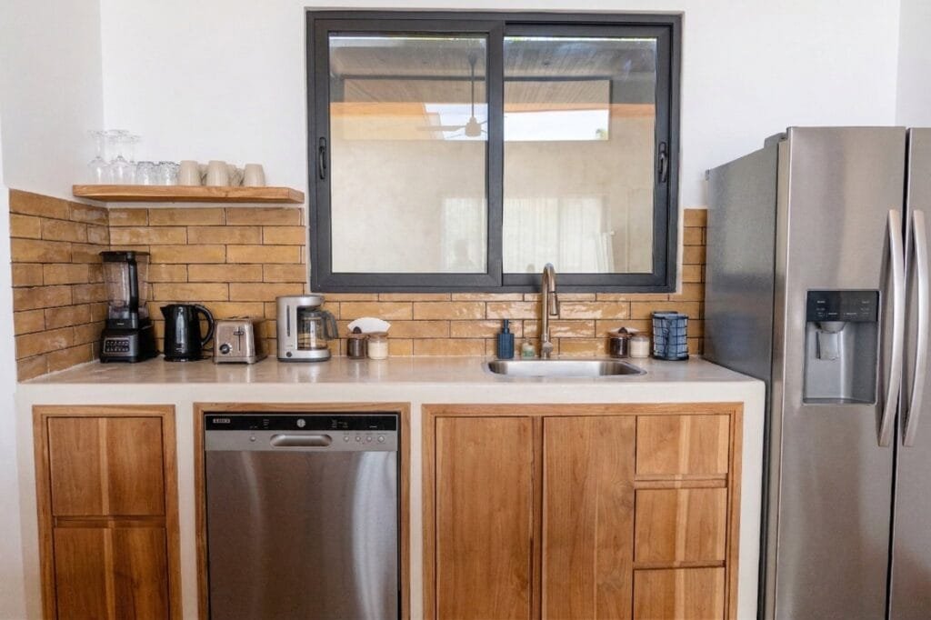 Cocina compacta del apartamento Colibrí con pared de ladrillo amarillo y electrodomésticos completos