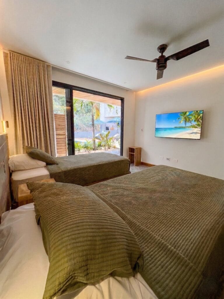 Habitación con camas individuales del apartamento Quetzal, con vista a la piscina y ventilador de techo