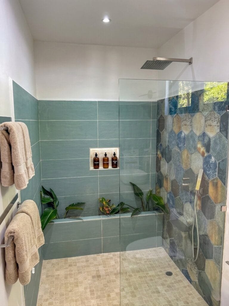 Ducha tipo lluvia a ras de piso del apartamento Quetzal con pared decorativa de piedra hexagonal