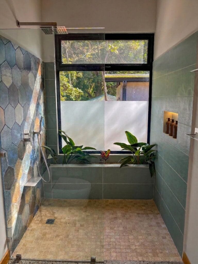 Baño del apartamento Tucán con pared de ducha de piedra azul hexagonal
