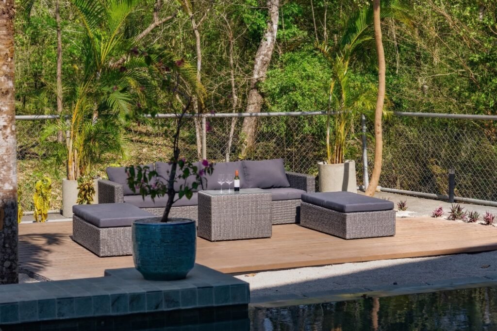 Sofá seccional de mimbre junto a la piscina de la villa Nori