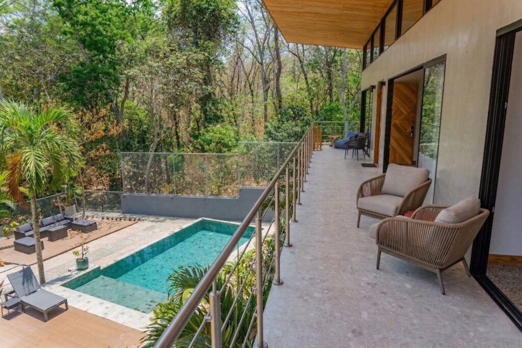 Balcón superior de la villa Nori con sillones de mimbre sobre la piscina